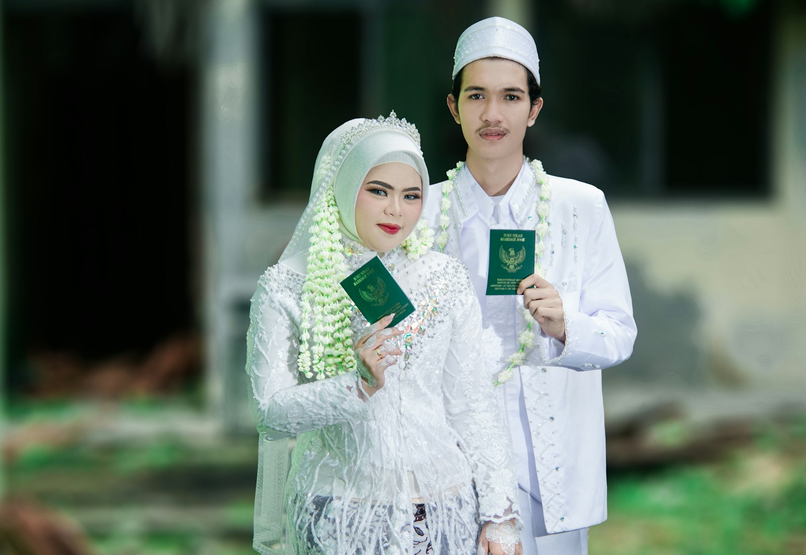 Newlyweds in traditional attire holding marriage books at a nikkah ceremony